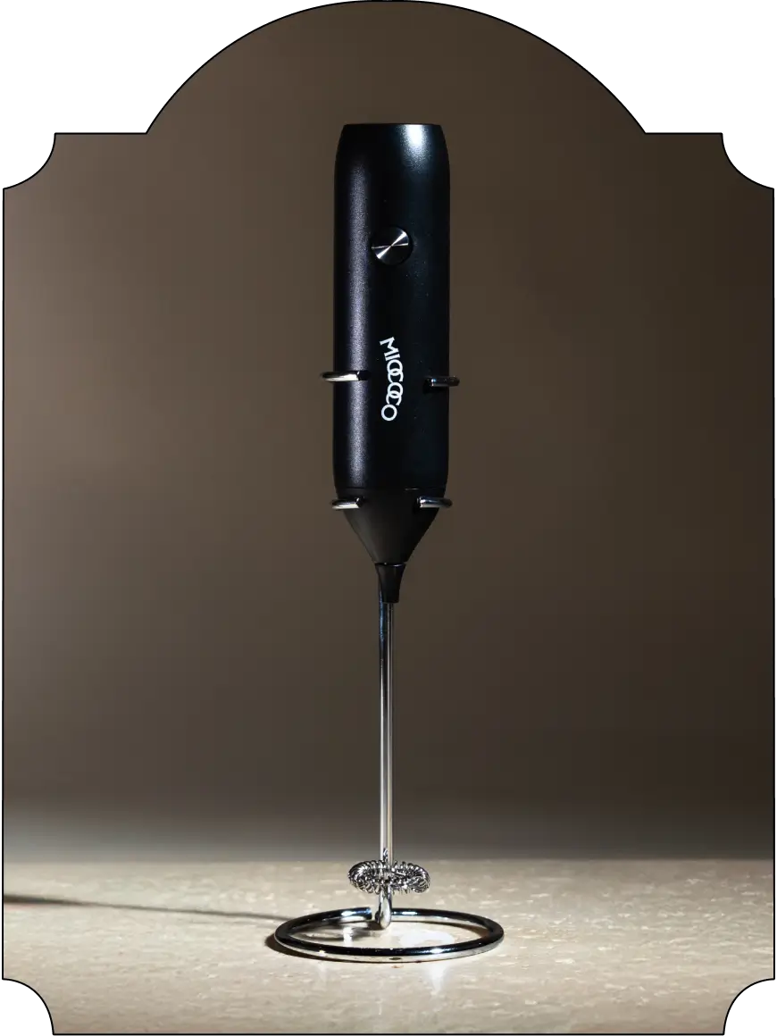 Black hand mixer on a reflective surface with a dark background