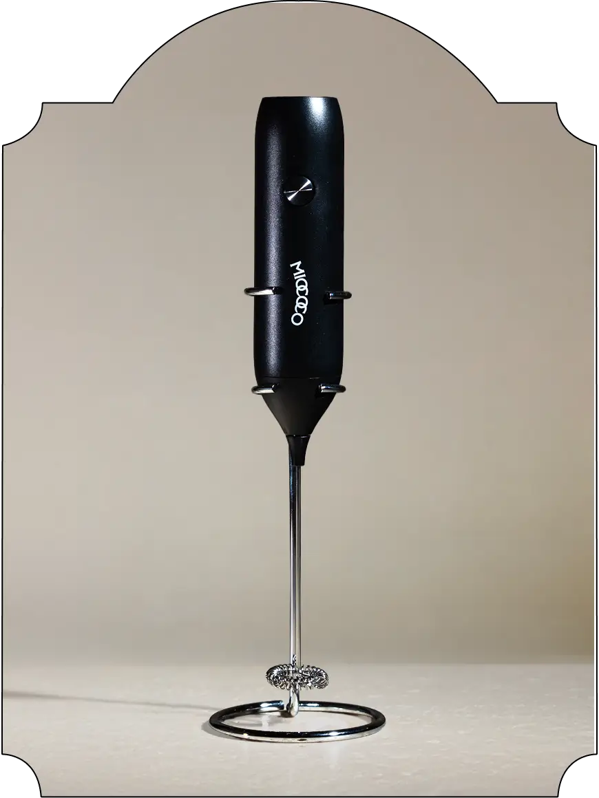 Black hand mixer on a reflective surface with a tan background