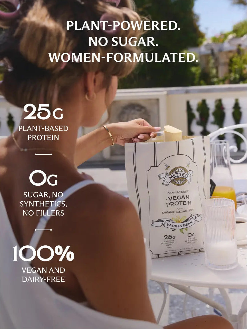 A woman in a white swimsuit stands at an outdoor table holding a bag of Miococo Vegan Protein Powder in vanilla flavor. The image features promotional text highlighting product benefits such as plant-powered, no sugar, and women-formulated, with '25G PLANT-BASED PROTEIN', '0g SUGAR, NO SYNTHETICS, NO FILLERS', and '100% VEGAN AND DAIRY-FREE'.